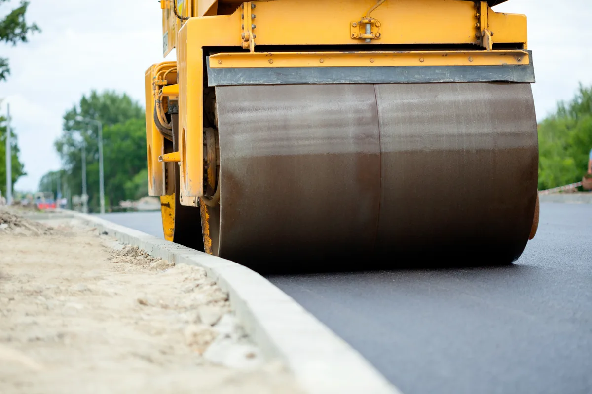 Paving crew laying hot-mix asphalt behind a paver and roller