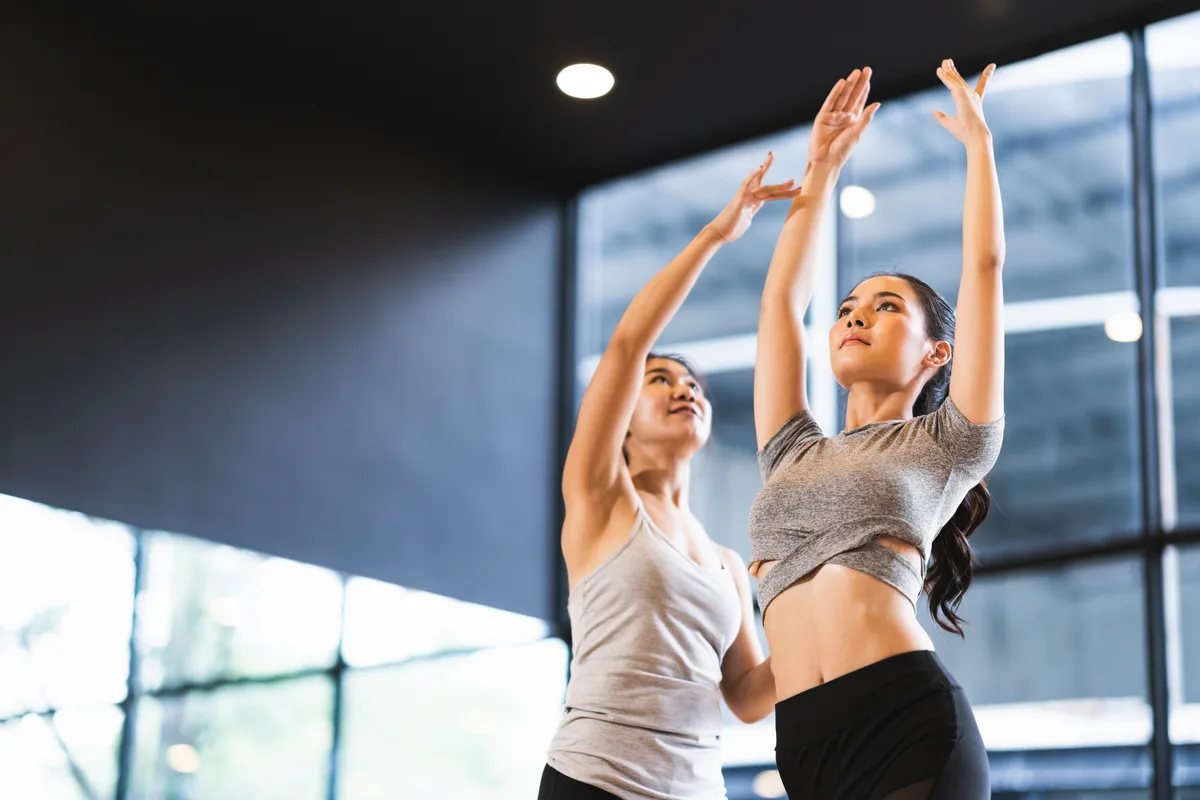Ballet dancers practising at the barre in a mirrored dance studio