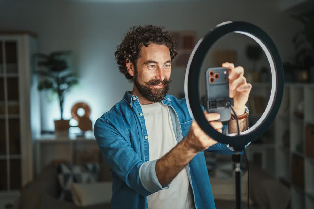 Content creator at a desk with a camera, ring light and laptop showing platform earnings dashboards
