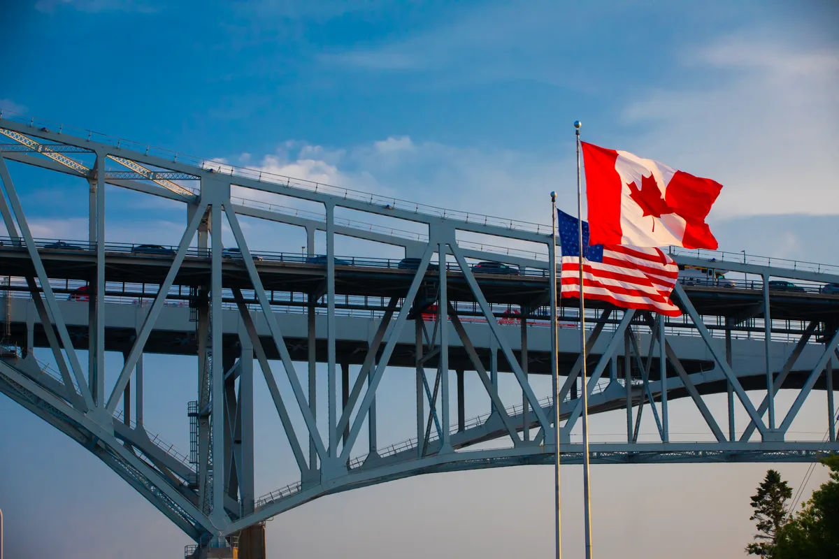 Canadian and American flags beside a printed tax checklist with a pen and passport on a desk