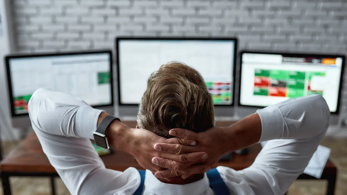 Day trader reviewing positions across multiple trading monitors