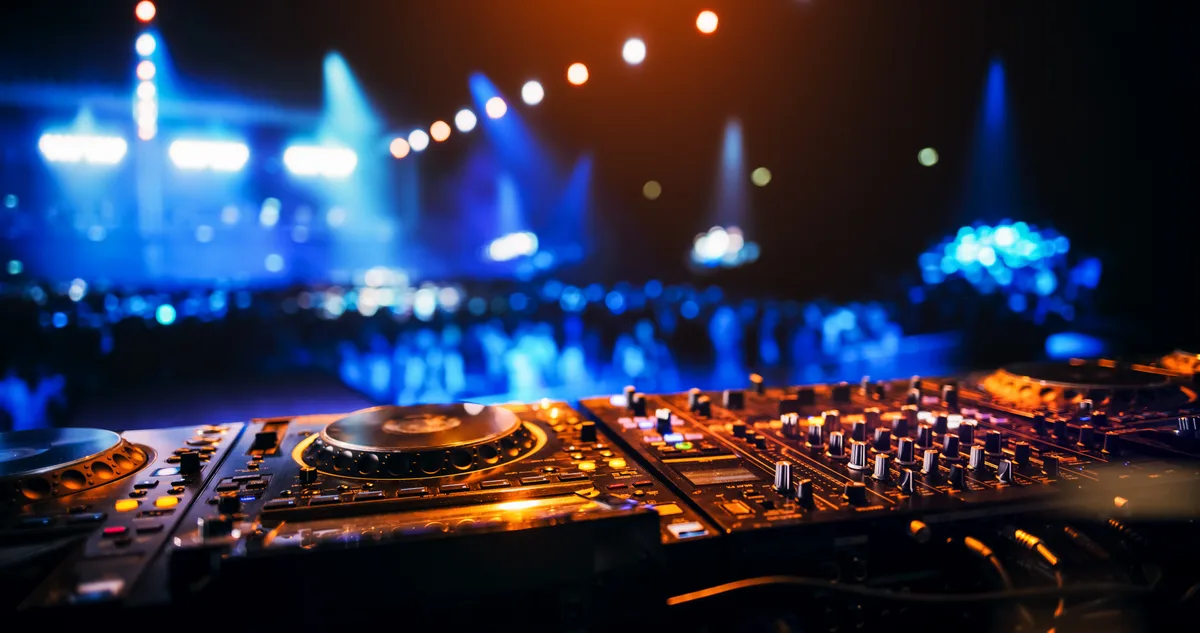 DJ performing at a mixing console with hands on the controls