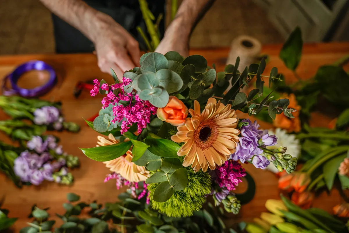 Florist arranging a bouquet of fresh flowers at a work bench