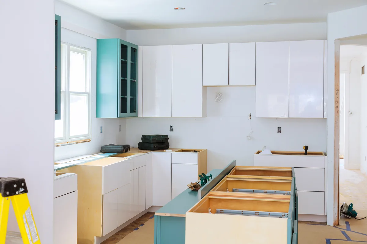 Installer fitting cabinetry during a kitchen renovation