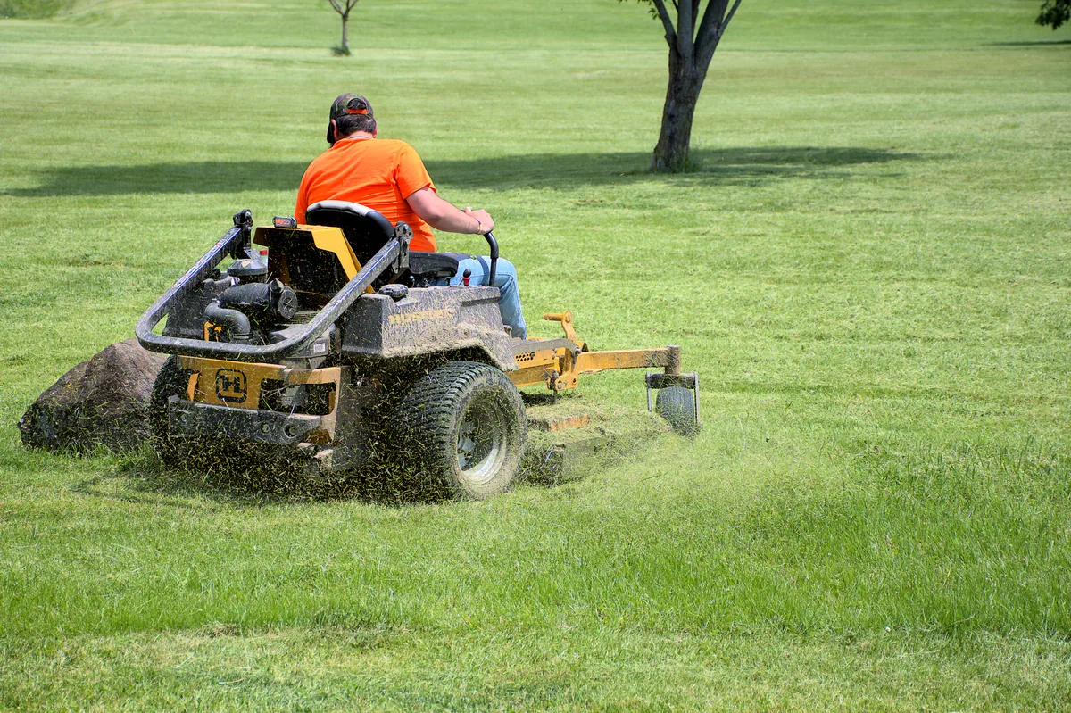 Landscaper mowing a lawn during peak maintenance season