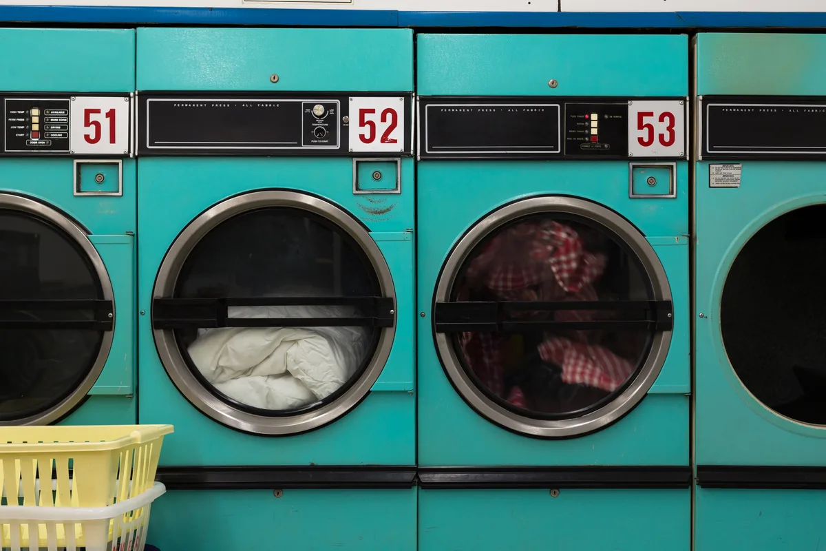 Bank of commercial washers and dryers inside a self-serve laundromat