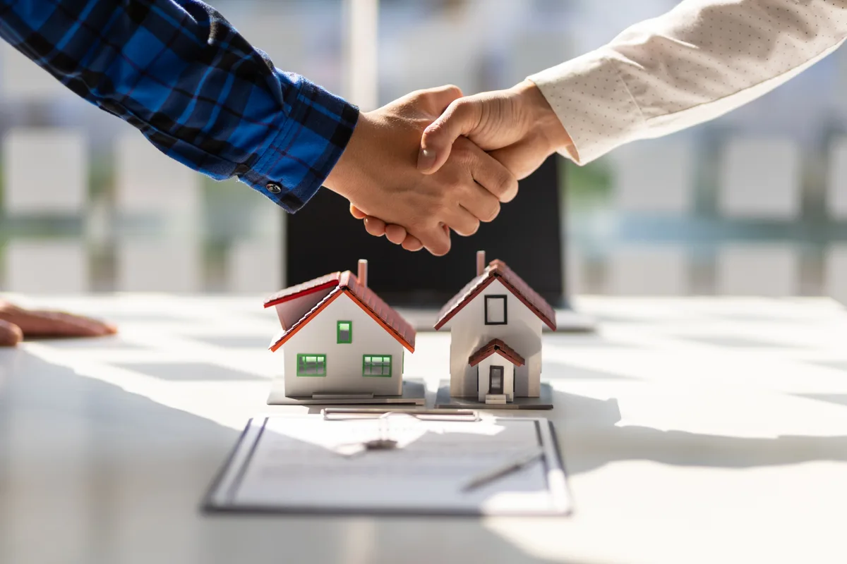 Private mortgage lender signing loan documents with keys on the table