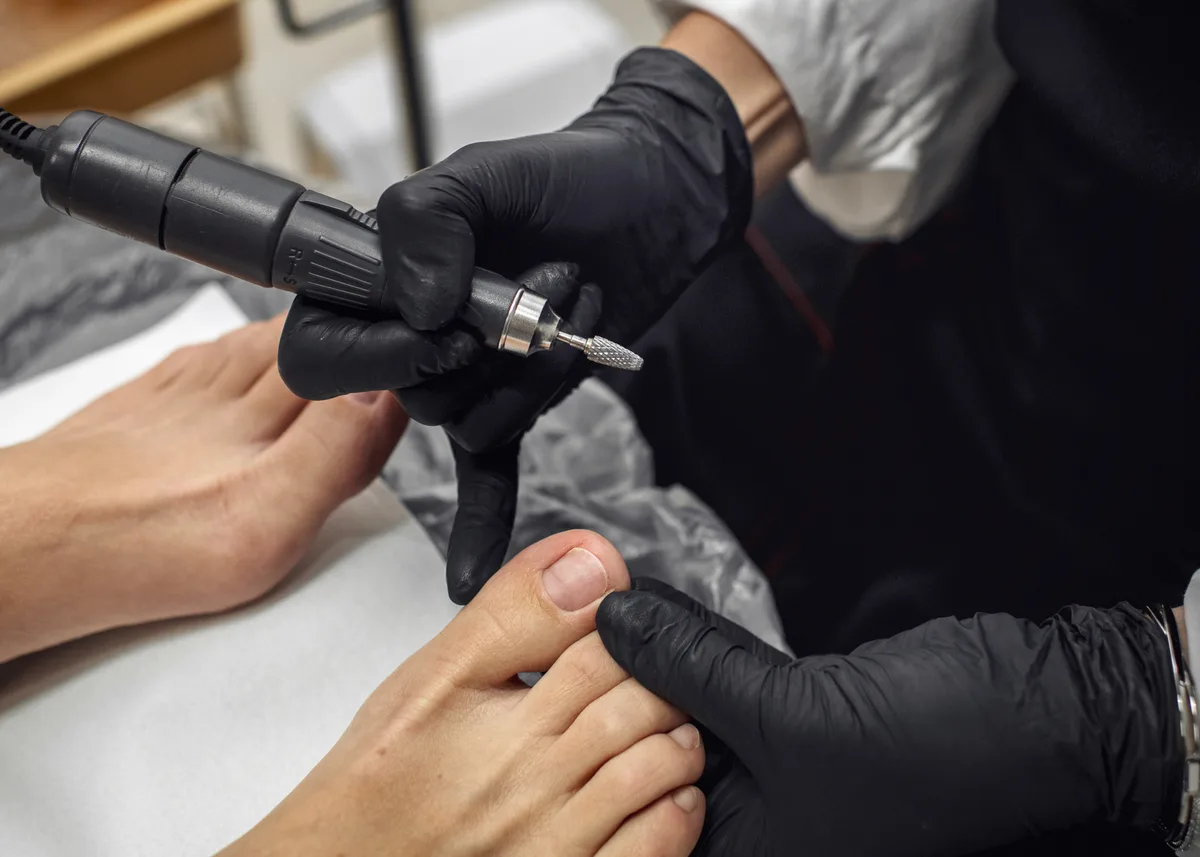 Nail technician giving a client a manicure at a salon table