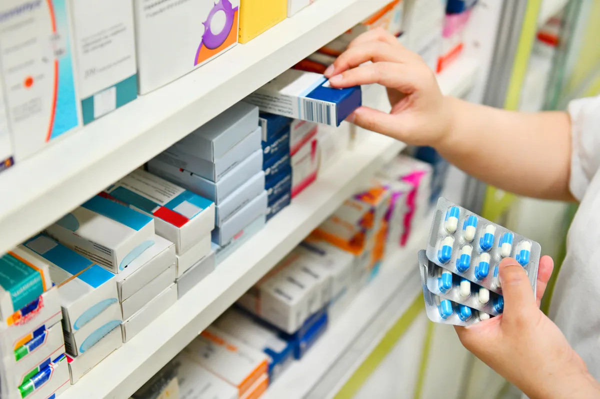 Pharmacist checking medication stock on pharmacy shelves