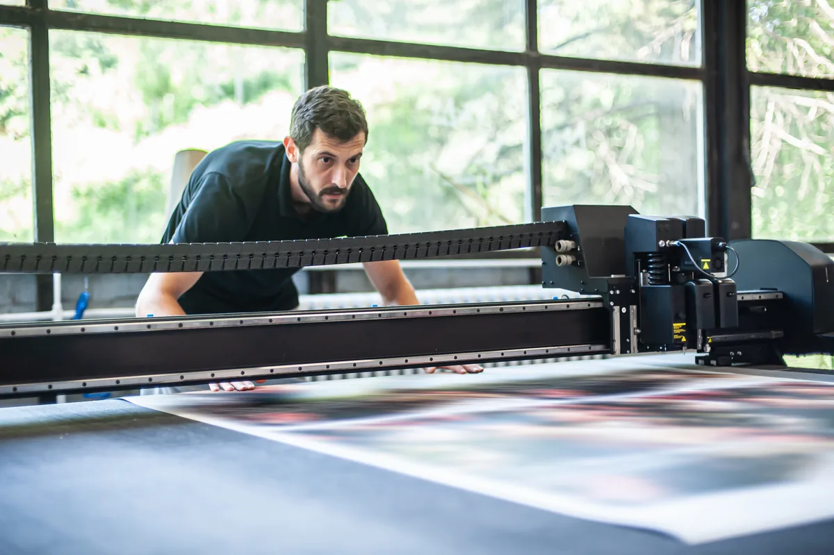 Press operator running a large-format print job in a sign shop