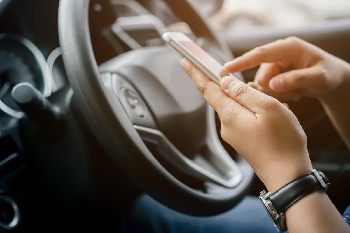 Rideshare driver behind the wheel with a trip running on the phone
