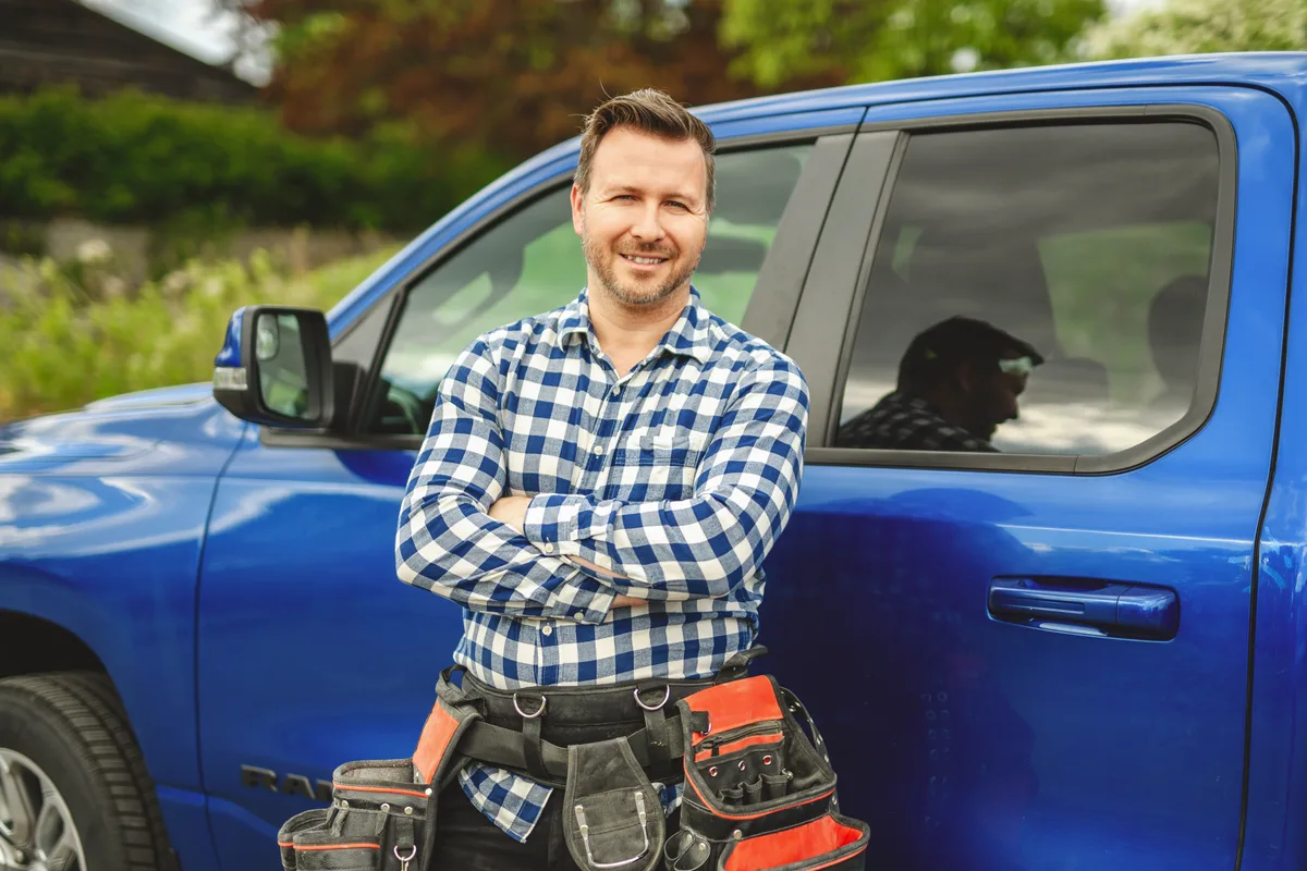 Landscaper loading equipment onto a truck at the end of the season with a cash flow spreadsheet in view