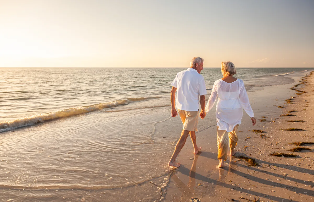 Canadian snowbird couple walking a southern US beach in winter