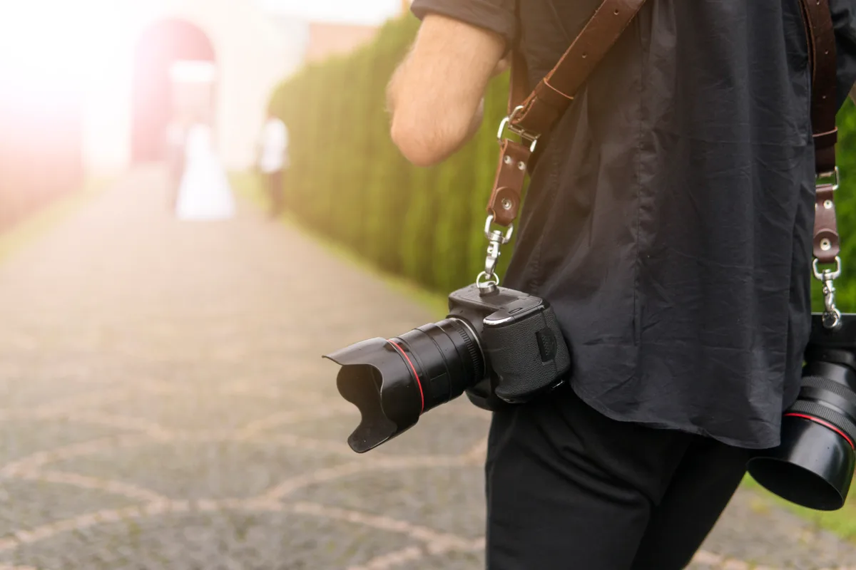 Wedding photographer shooting a couple outdoors with a professional camera