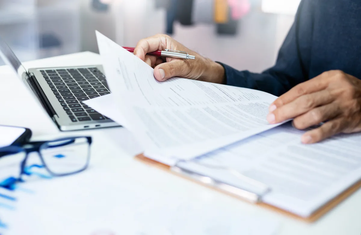 Desk with year-end financial statements, a calculator and a planning checklist
